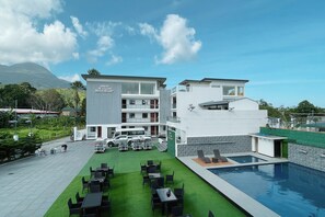A modern hotel with a pool, outdoor seating, and a mountain view. - Orient De Galera Beach Resort (Puerto Galera)