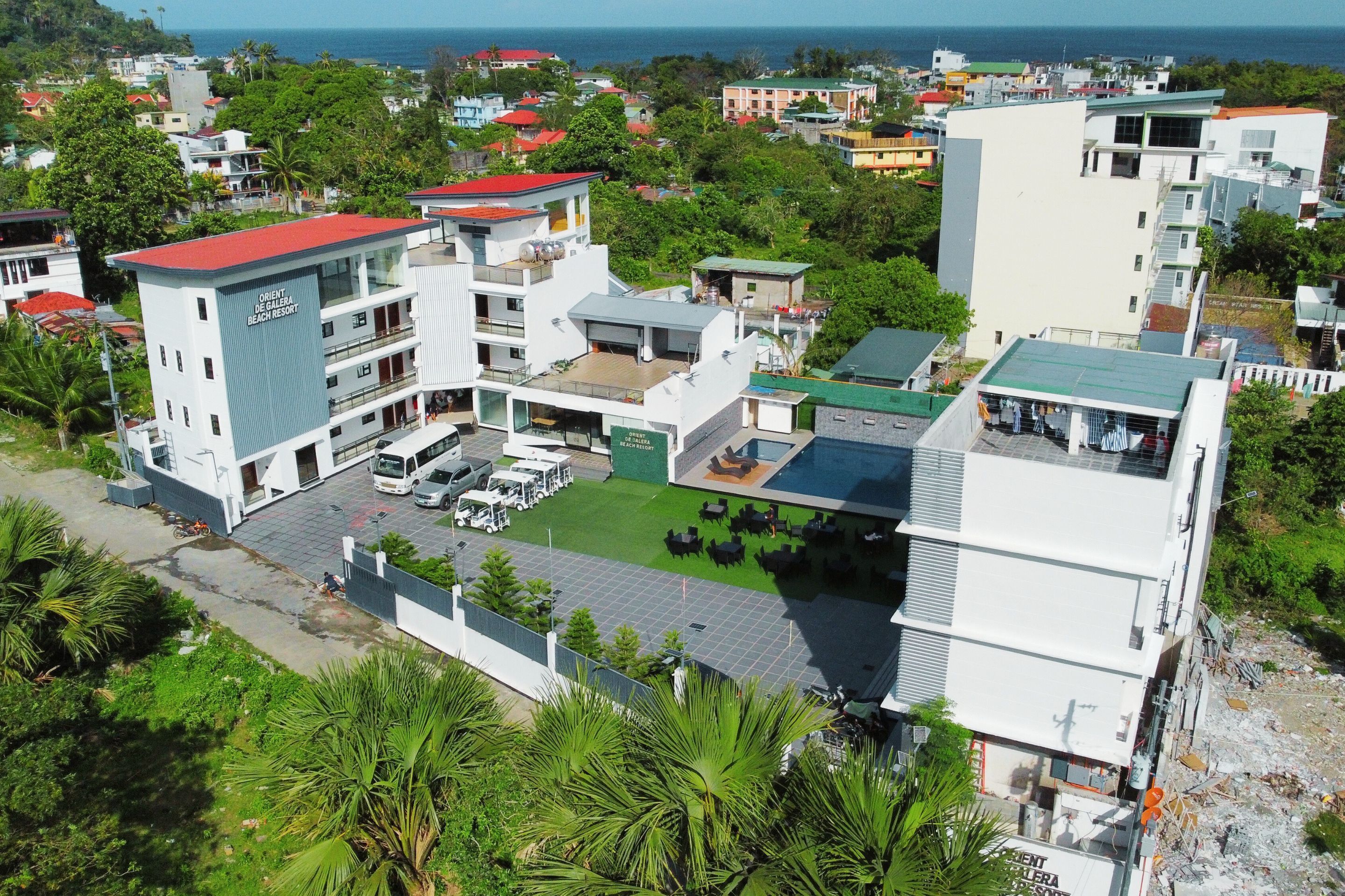 Ein Resort mit mehreren Gebäuden, einem Poolbereich und Blick aufs Meer.
