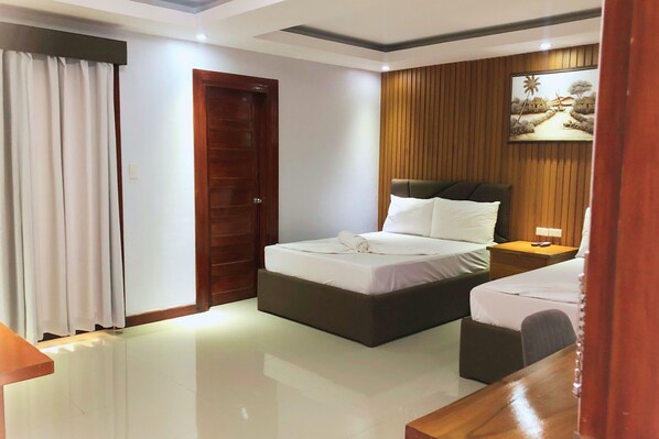 A hotel room with a bed, a bedside table, a nightstand, a mirror, a curtain, and a wooden panel wall with a painting.