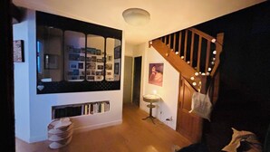 A hallway with a bookshelf, a staircase with lights, and a small table with a lamp. - Comfortable air-conditioned villa - private heated swimming pool 3 kms from Sarlat center (PROISSANS)