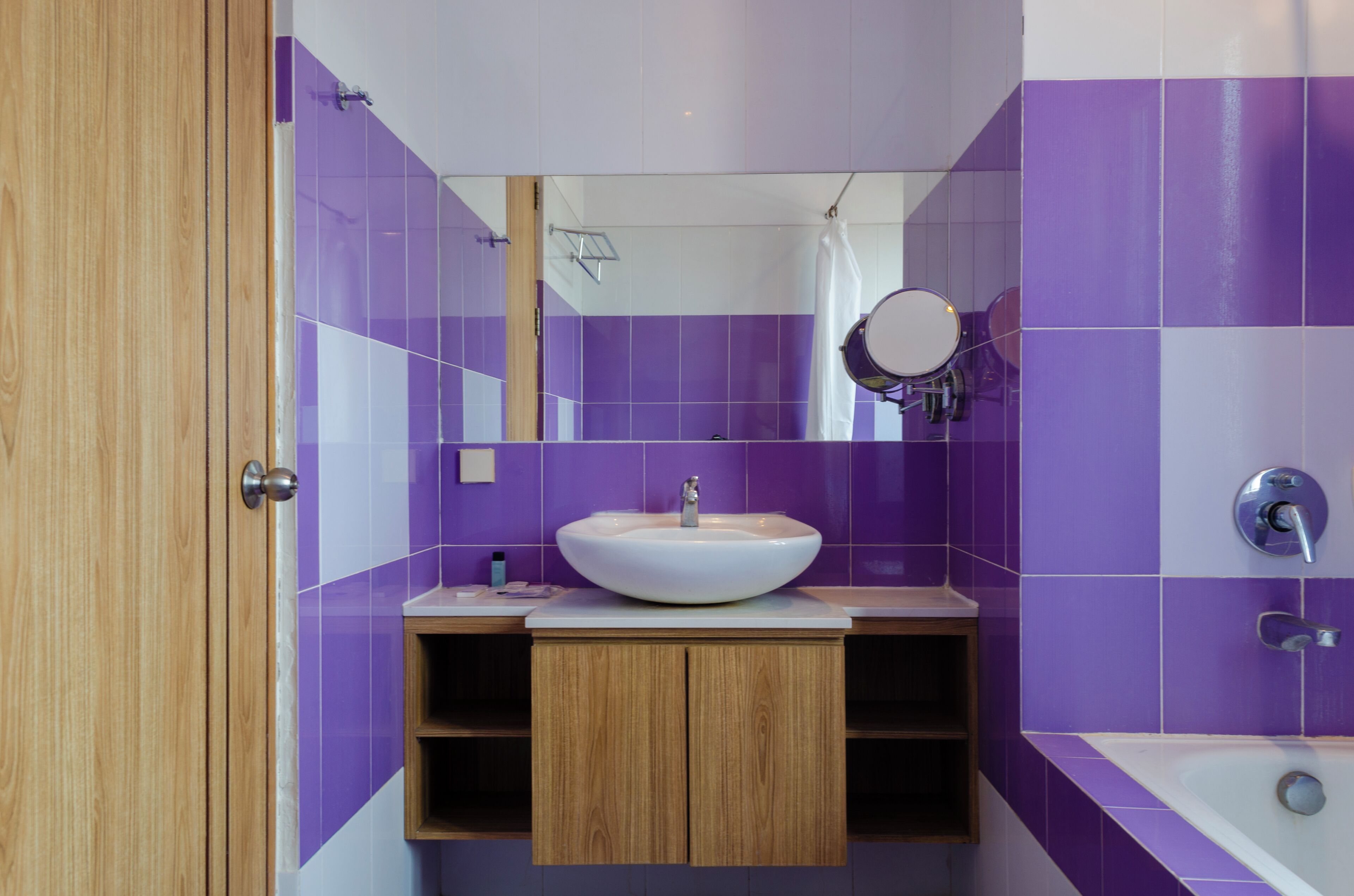 A modern bathroom with a wooden vanity, a white sink, a mirror, and a bathtub.