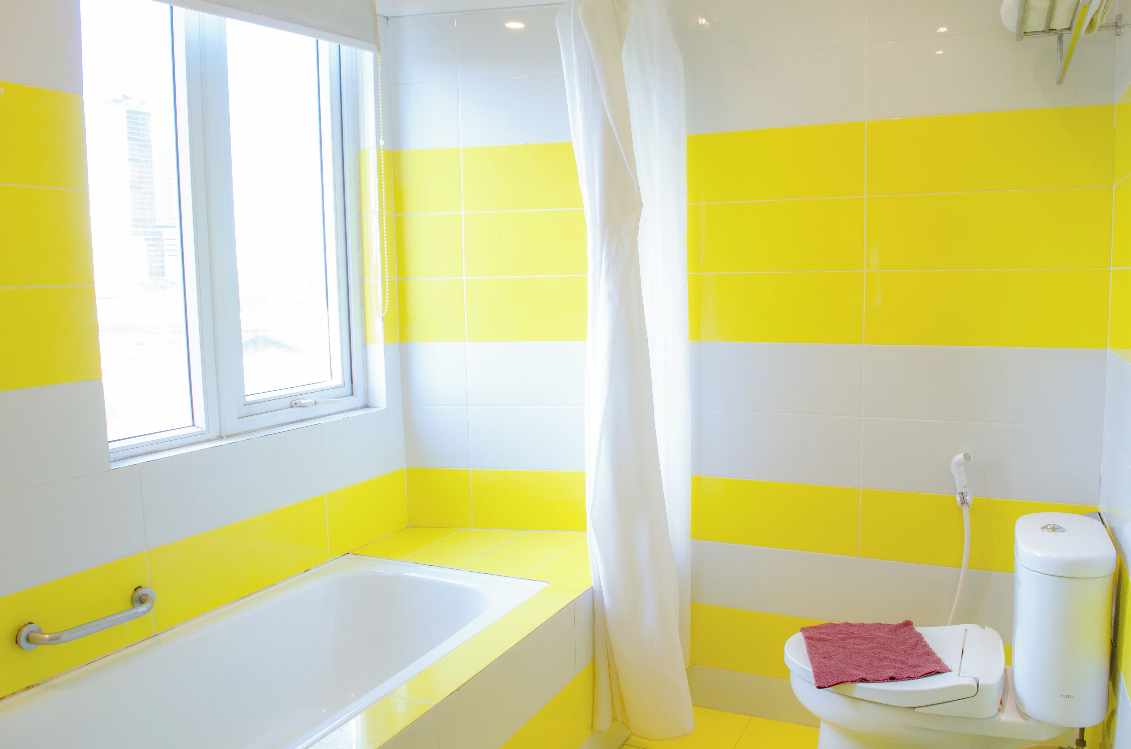 A bathroom with a bathtub, toilet, and a window.