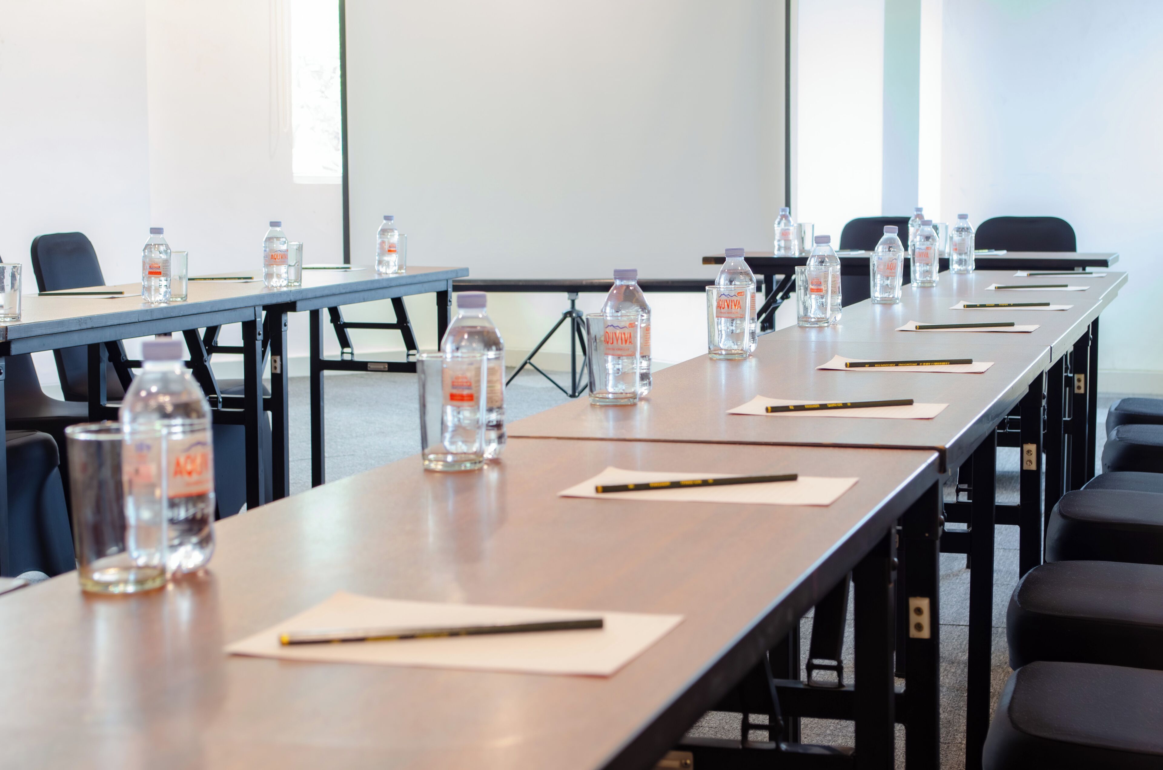 A conference room with long tables, water bottles, and pens.