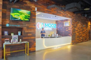 Un mostrador de recepción de diseño moderno, un televisor montado y un letrero del Hotel Mooz.