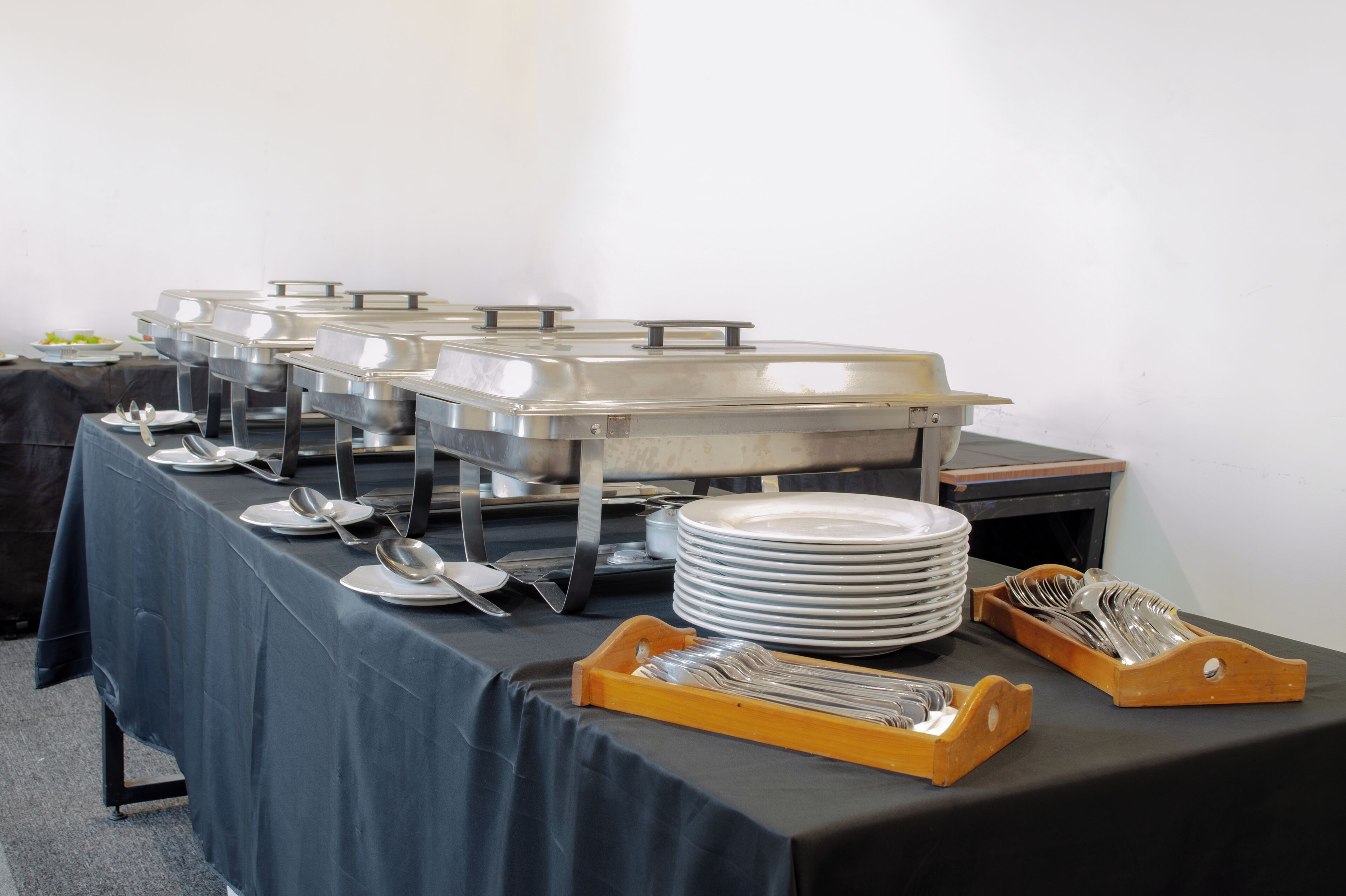 Ein reichhaltiges Buffet mit mehreren Servierstationen, Tellern und Besteck.