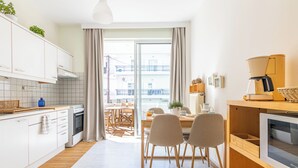 A modern kitchen with white cabinets, a wooden countertop, and a dining area with chairs and a table.