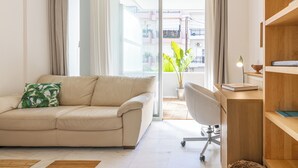 A modern living room with a beige sofa, a wooden desk, and a potted plant.