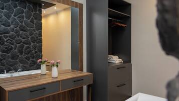 Une salle de bain moderne avec un mur en pierre, un meuble-lavabo en bois et une armoire grise.