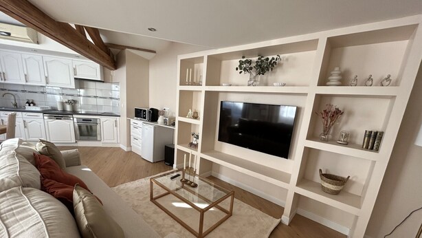 A modern living room with a flat-screen TV, a sofa, and a coffee table.