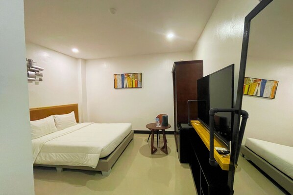 A hotel room with a bed, a desk with a chair, a TV, and artwork on the walls. - Hotel Halo Angeles City (Angeles City)