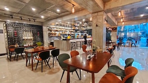 A spacious restaurant with high ceilings, exposed concrete beams, and a bar area. Tables and chairs are arranged for dining. - Hotel Halo Angeles City (Angeles City)