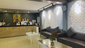 A reception area with a counter, a sofa, a coffee table, and a brick wall. - Hotel Halo Angeles City (Angeles City)