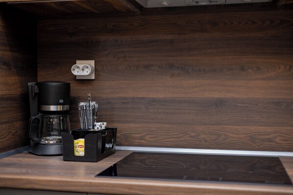 Eine Küche mit Kaffeemaschine, einer Packung Lipton Tee und einer Steckdose an der Wand.