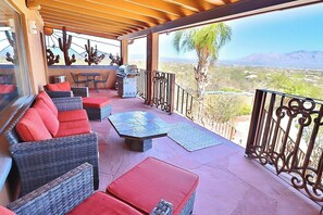 A covered outdoor seating area with wicker furniture and a grill.