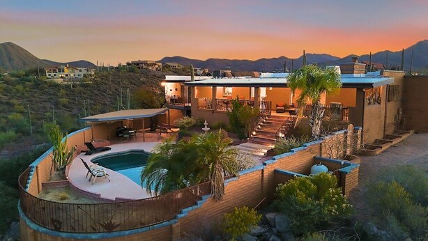 Una casa moderna amb piscina, zona d'estar a l'exterior i vistes a les muntanyes.