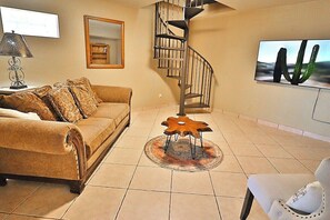 A living room with a sofa, a coffee table, a chair, a spiral staircase, and a framed picture on the wall. - Private Hilltop Oasis Overlooking City Lights (Tucson)