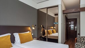A hotel room with a large bed, a chair, a mirror, and a door leading to another room. - Hotiday Room Collection - Oporto (Porto)
