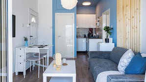Un salon moderne avec un bureau blanc, un canapé gris et un luminaire suspendu.