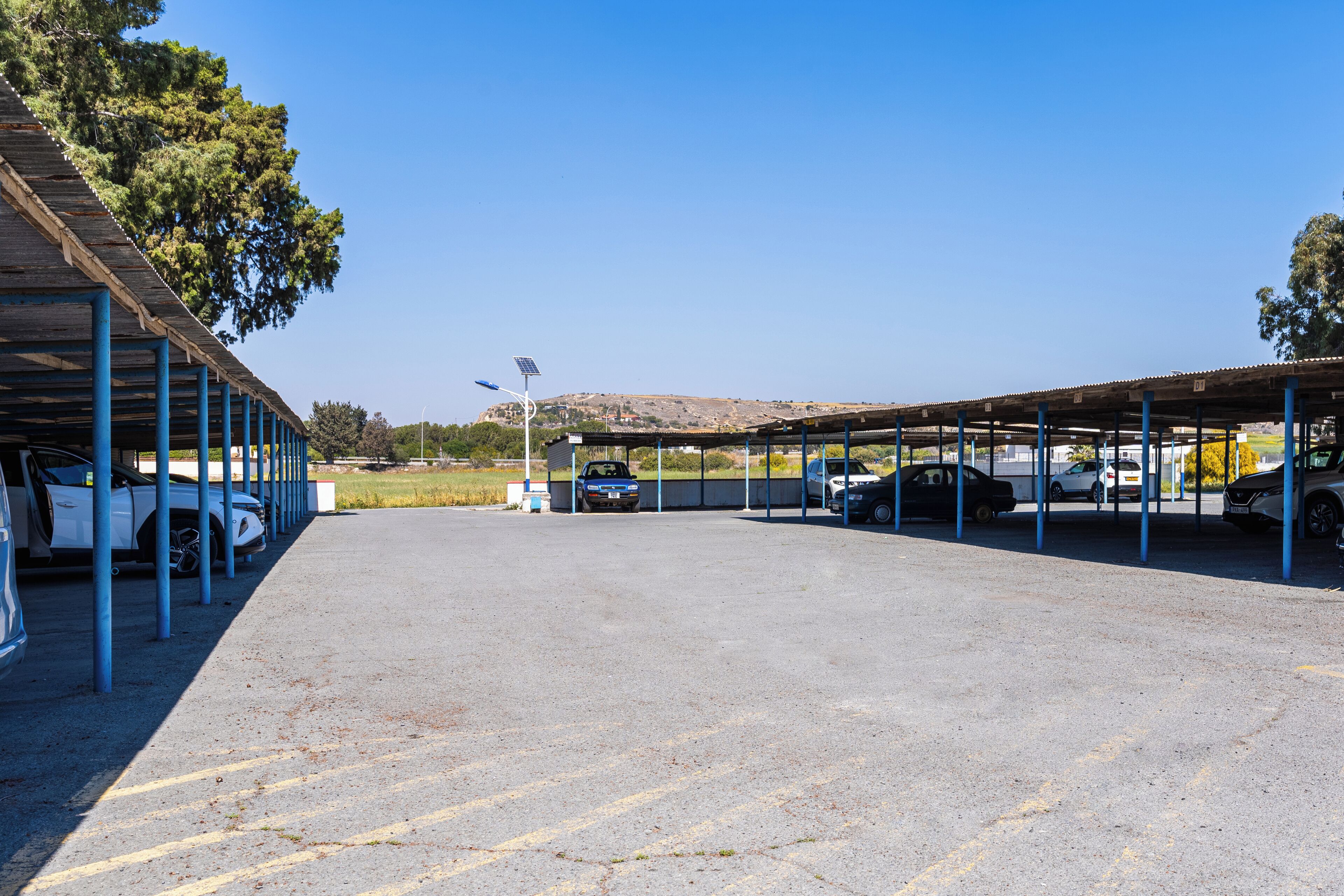 A parking area with covered car bays and a clear sky.