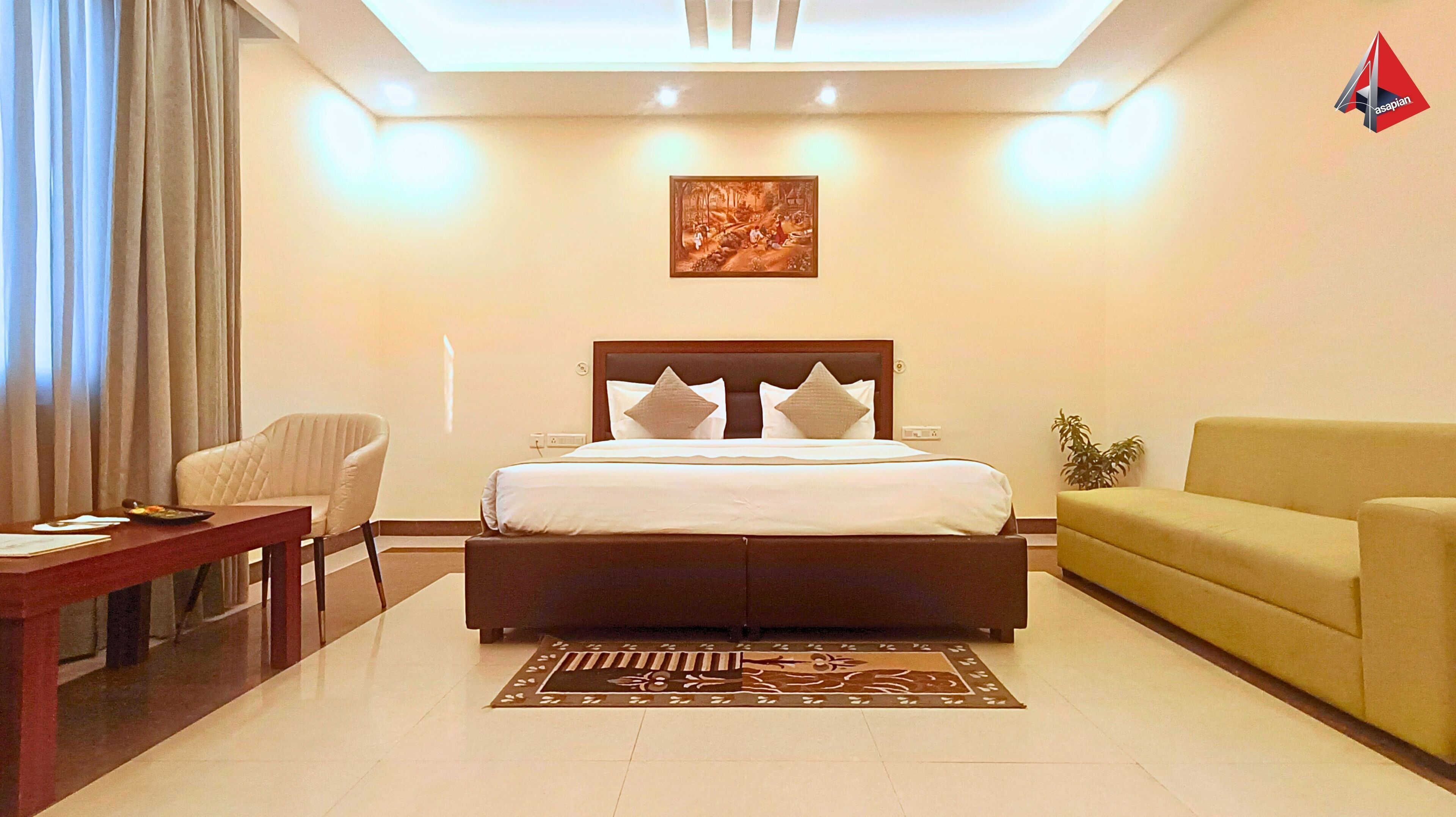 A hotel room with a bed, a sofa, a chair, a desk, and a painting on the wall.