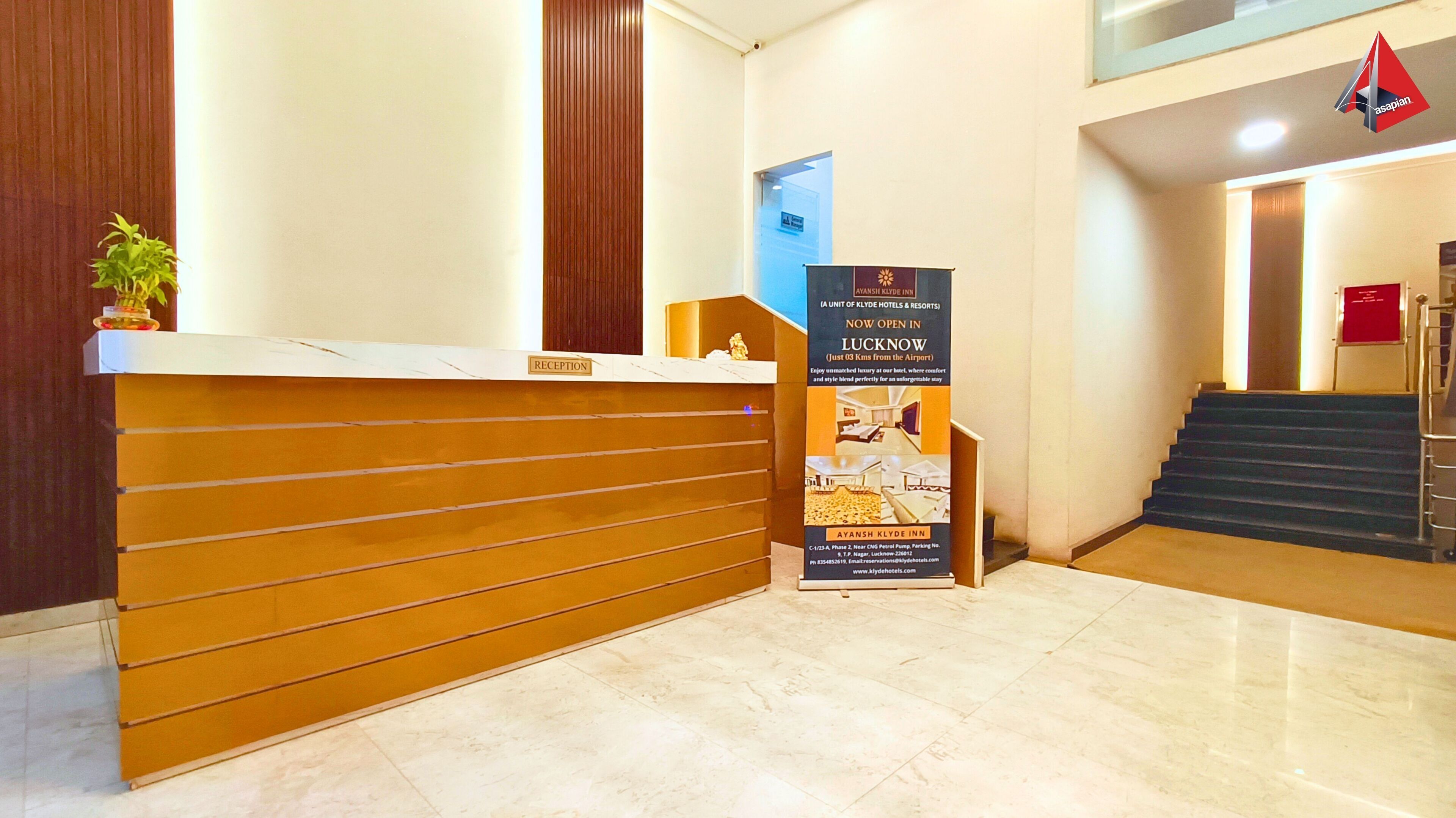 A reception desk with a sign for Ayansh Klyde Inn, a staircase, and a plant.