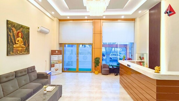 A reception area with a sofa, a reception desk, a chandelier, a Buddha statue, and a glass door leading outside. - AYANSH KLYDE INN (Lucknow)