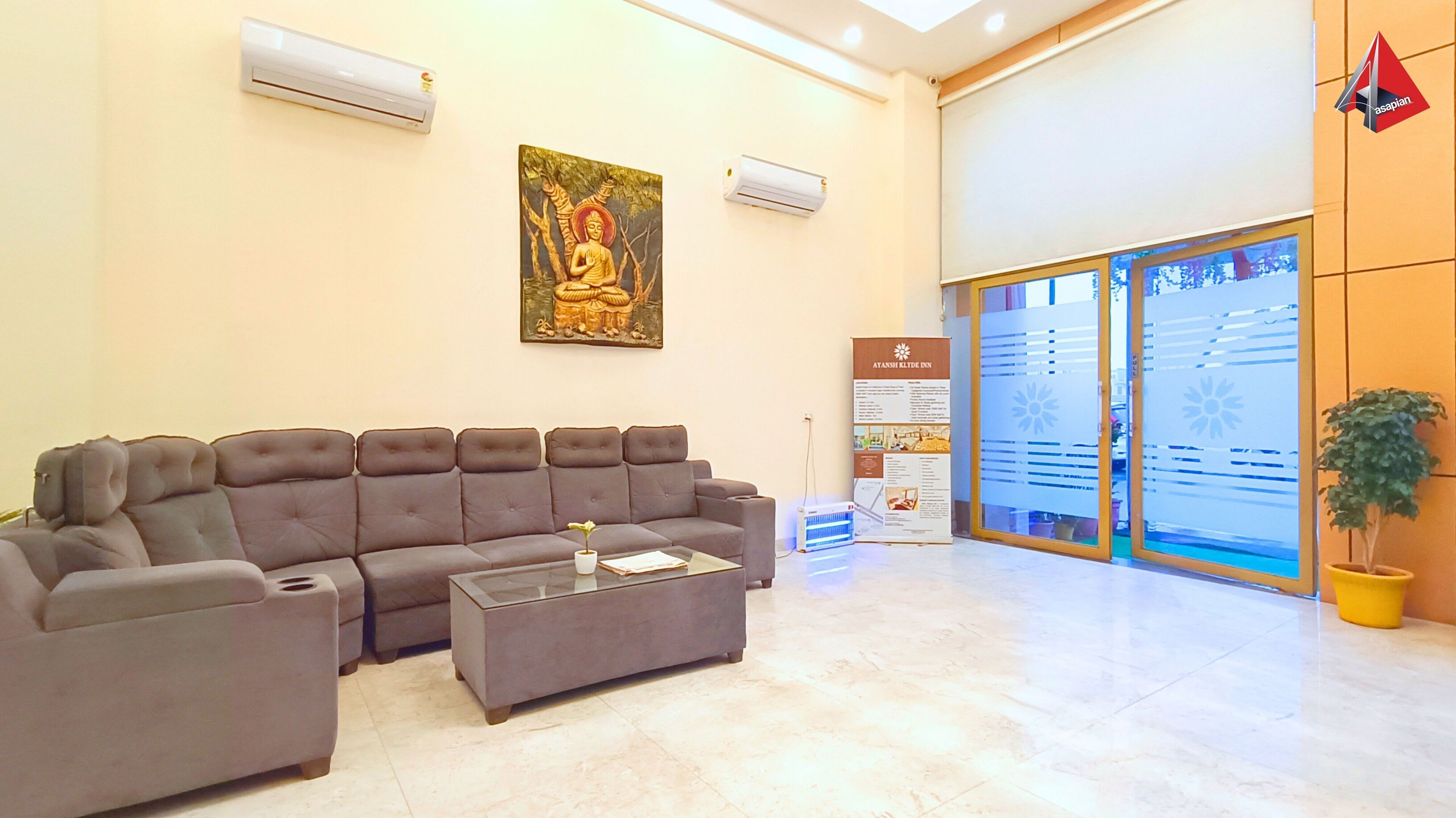 A reception area with a sofa, a coffee table, and a Buddha painting. There is a sign for Tatansh Klyde Inn and a potted plant.