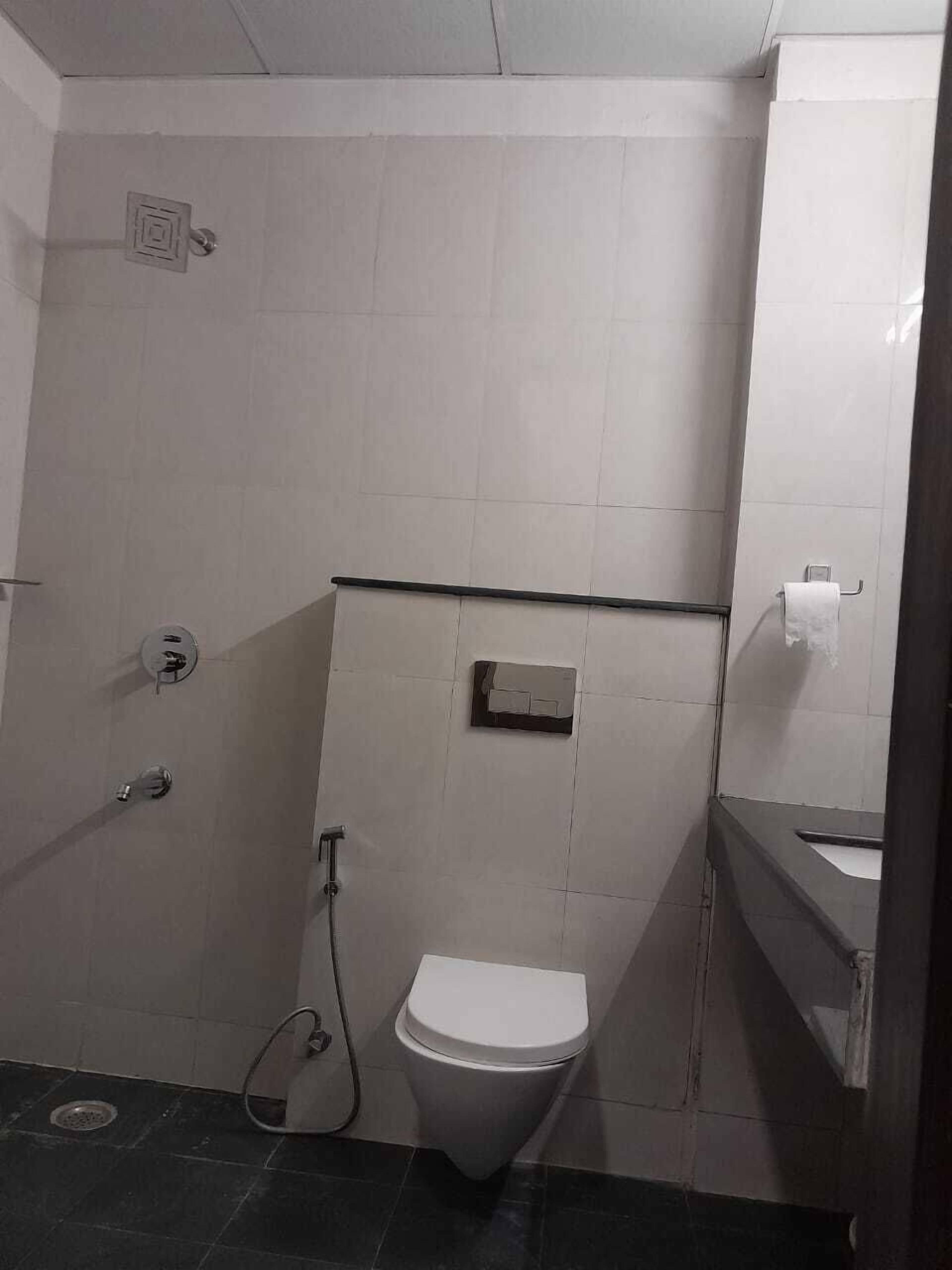 Une petite salle de bain compacte, équipée de toilettes, d’une douche et d’un lavabo.