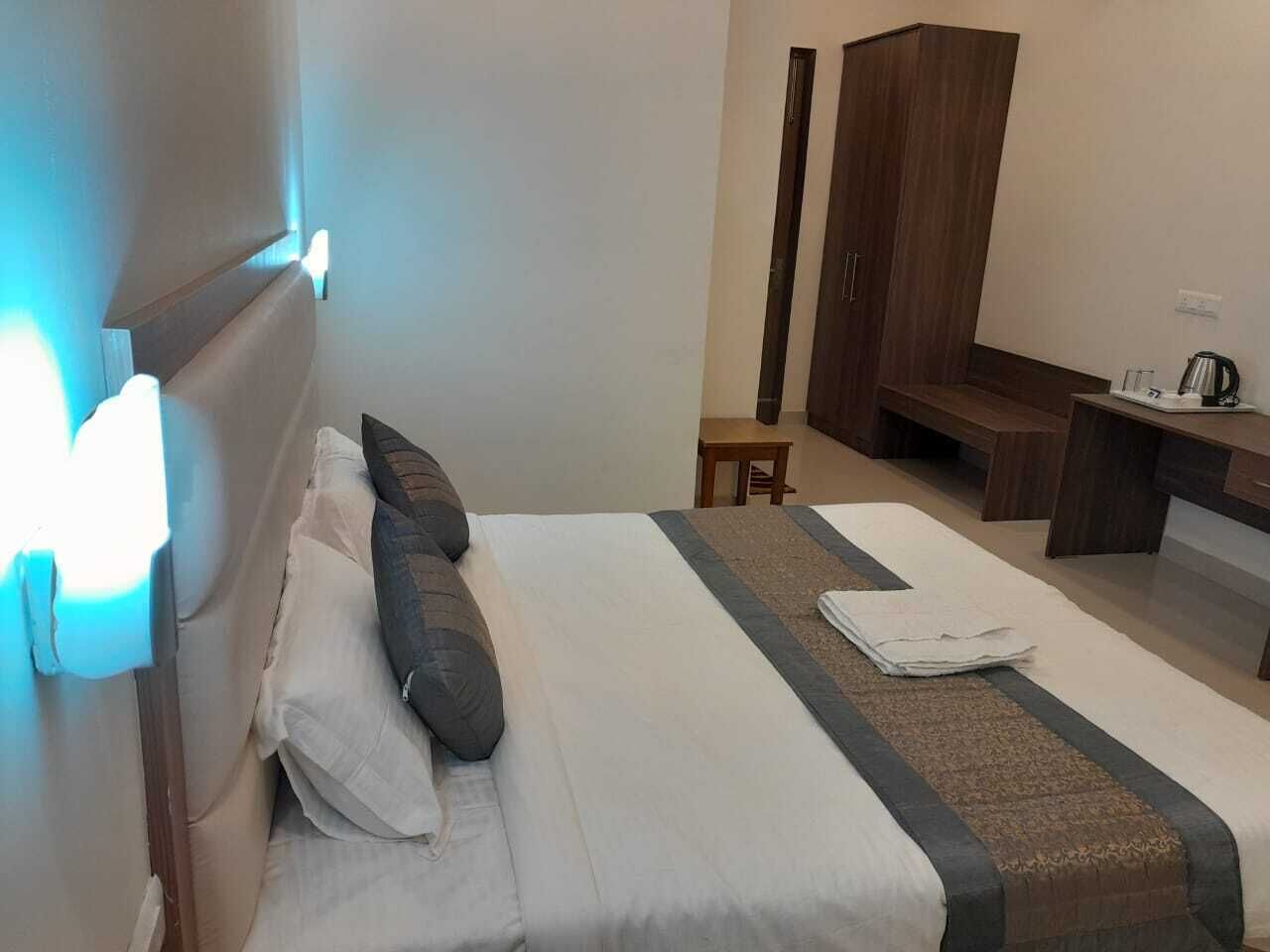 A hotel room with a bed, a desk, a chair, and a wardrobe.