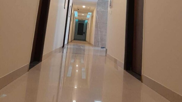 A modern hotel hallway with a polished floor, recessed lighting, and a marble accent wall. - Hotel The Luxem (Gurugram)