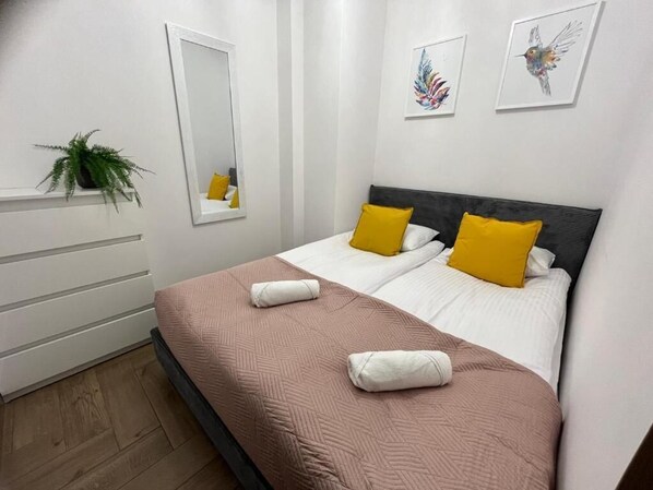 Habitación de hotel con cama, dos almohadas, un espejo y una obra de arte en la pared.