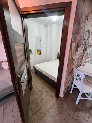 Un dormitorio con cama, mesita de noche, silla, espejo y pared con diseño texturizado.