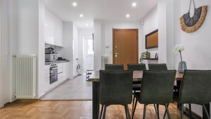 Une cuisine moderne avec des meubles blancs et un coin repas comprenant une table en bois et des chaises noires.
