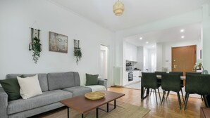 Un salon moderne avec un canapé gris, une table basse en bois et un coin repas comprenant une table et des chaises.