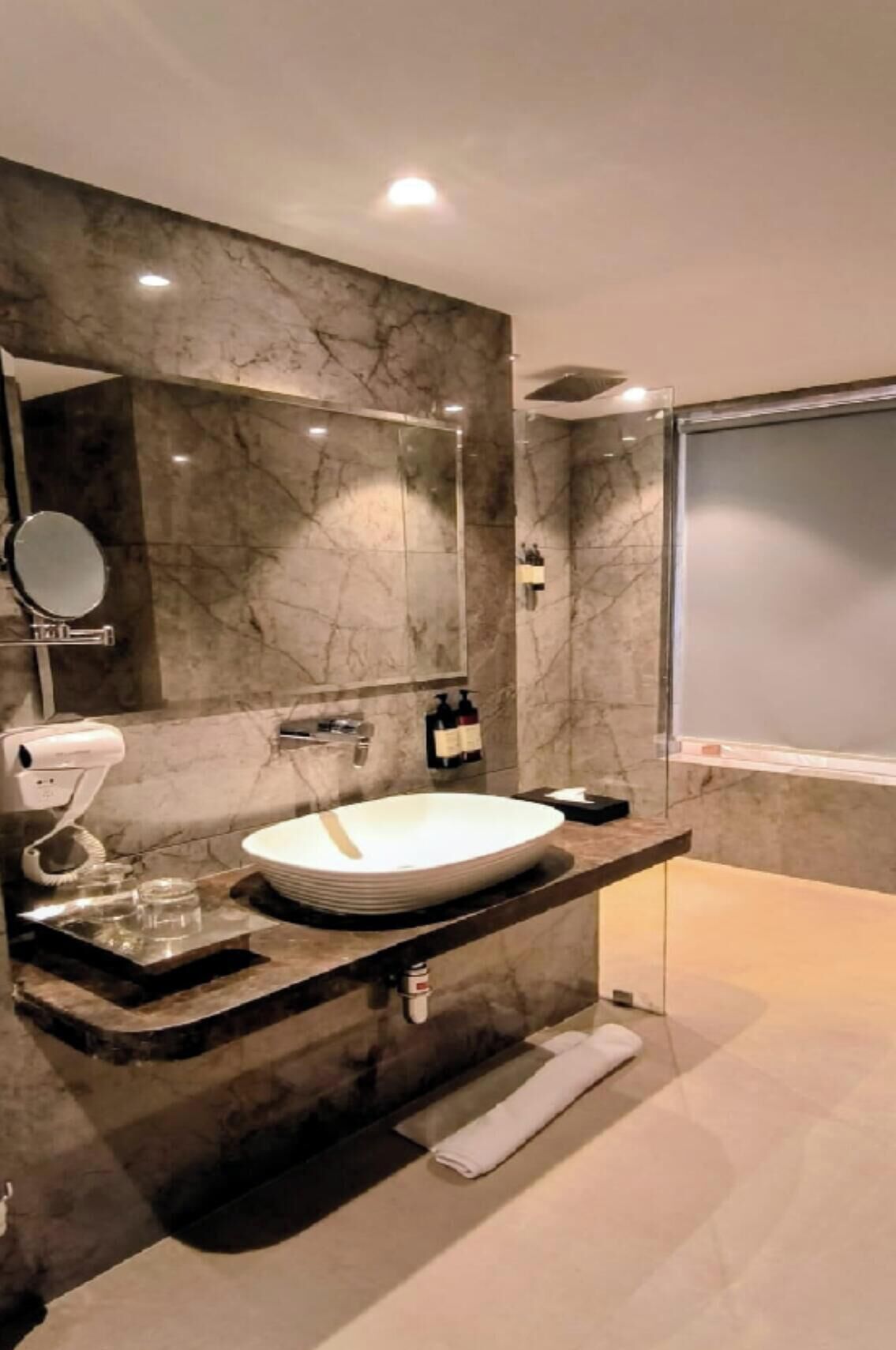 A modern bathroom with a marble vanity, a large mirror, a sink, and a towel rack.