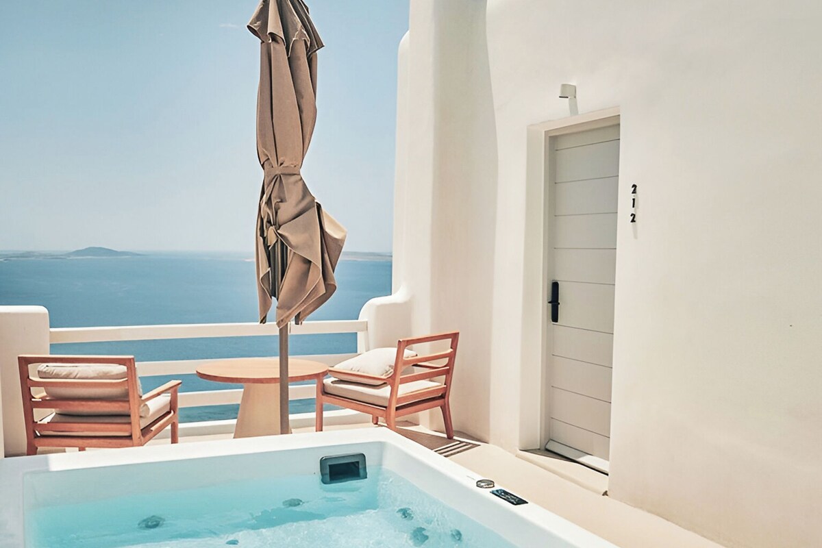 A rooftop terrace with a hot tub, lounge chairs, and an umbrella.
