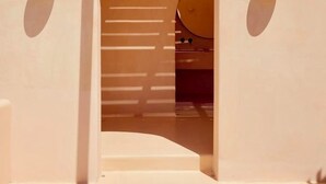 A model of a building with a central arched doorway, two small spherical light fixtures on either side, and a sloped roof. - Hotiday Mykonos Fanari (Mykonos)