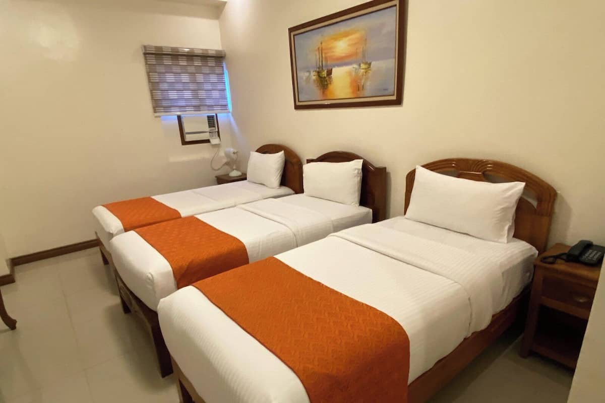 A hotel room with two beds, a painting on the wall, a window with blinds, and a bedside table with a phone.