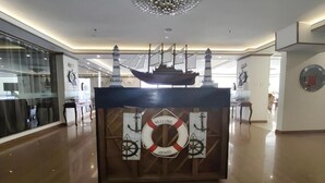 Un comptoir d’accueil agrémenté d’une maquette de navire, de bouées de sauvetage et d’ancres.