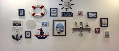 A wall decorated with nautical-themed items including a lifebuoy, a ship, a lighthouse, and a clock.