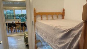A bunk bed with a wooden headboard and a white bedspread. A hallway leads to a dining area with a table and chairs. - Studio 1 to 4 persons (Bandol)