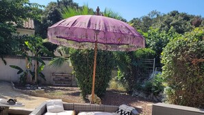 A patio area with wicker furniture, including sofas and a table with a pitcher and a decorative item. - Rental house with pool and Jacuzzi (Restinclières)