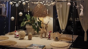 A dining area with a table set for two, decorated with a Christmas theme including ornaments and a Santa figurine. - Rental house with pool and Jacuzzi (Restinclières)