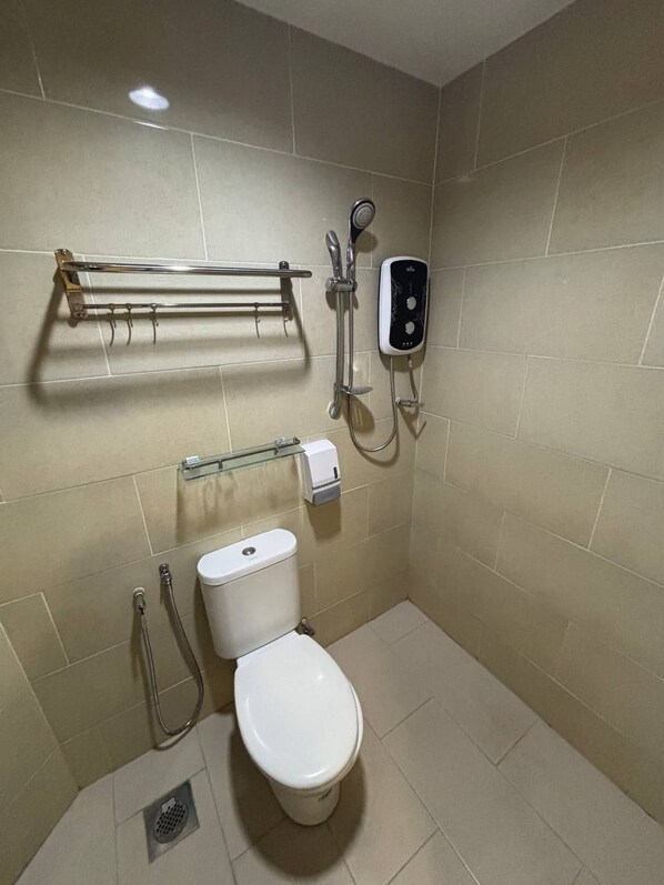 Een kleine, moderne badkamer met een toilet, een handdouche, een handdroger en een handdoekhouder.