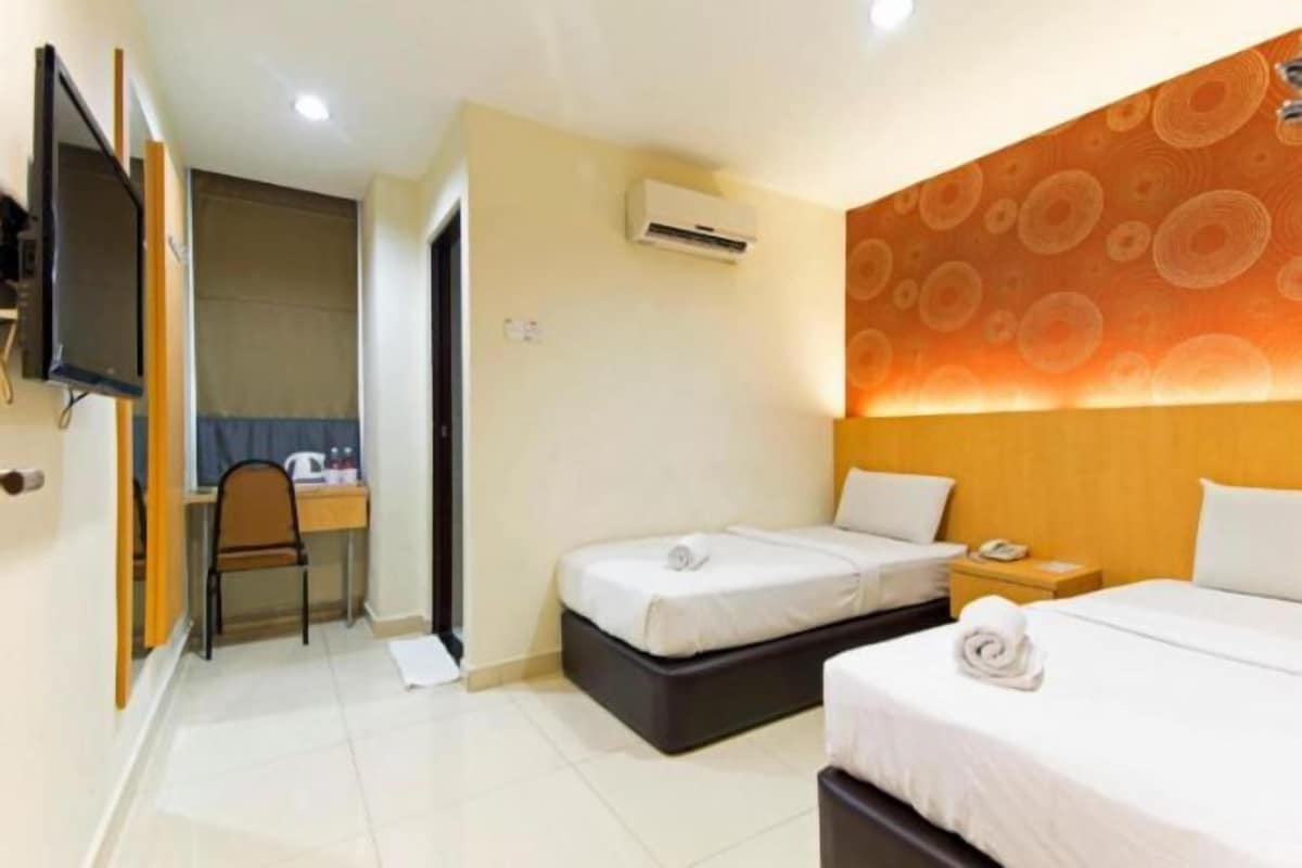 A hotel room with two beds, a desk, a chair, and an air conditioning unit.