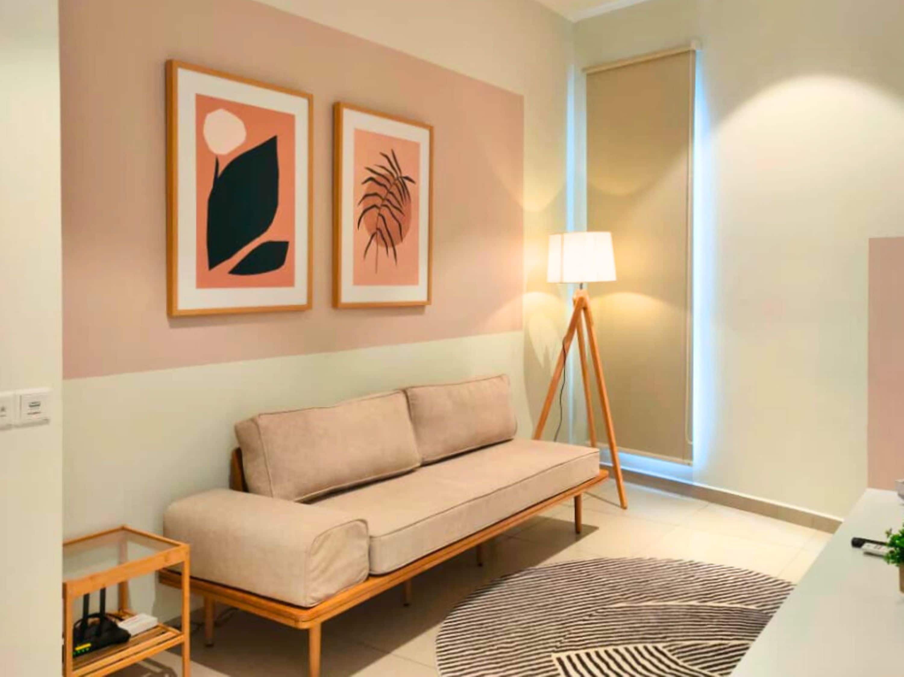 Una habitación con un sofá, una lámpara y dos cuadros en la pared.