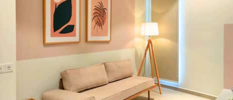 A room with a sofa, a lamp, and two framed artworks on the wall.