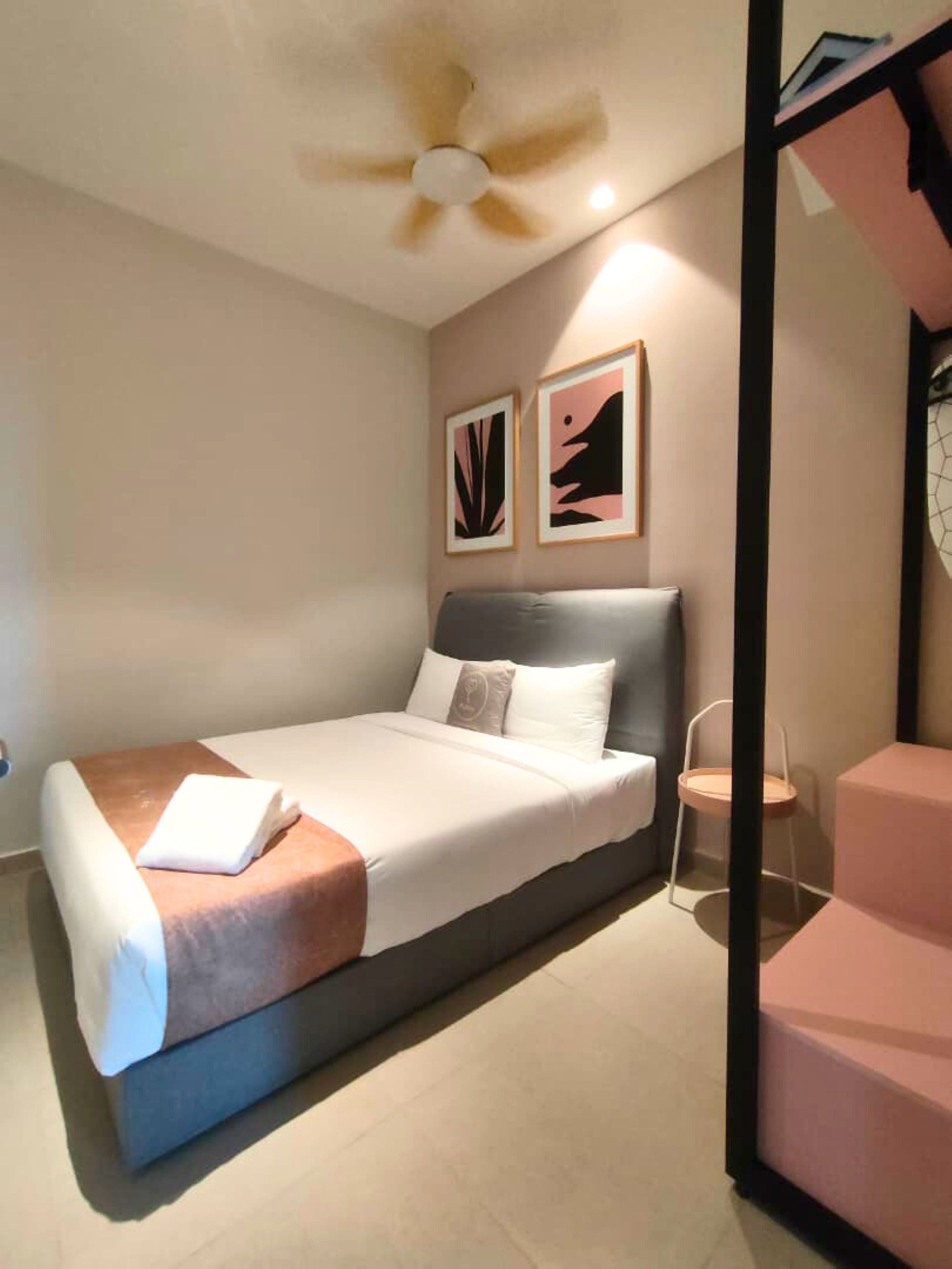 Ein modernes Schlafzimmer mit einem Bett, einem Deckenventilator und zwei gerahmten Kunstwerken an der Wand.