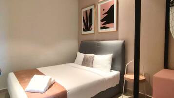 A modern bedroom with a bed, a ceiling fan, and two framed artworks on the wall.