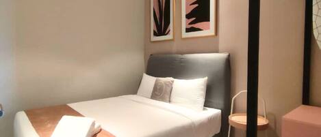 Un dormitorio moderno con una cama, un ventilador de techo y dos obras de arte enmarcadas en la pared.